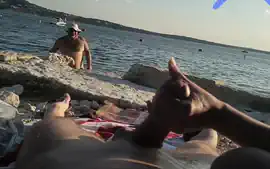 On a nude beach the wife stokes my cock while a voyuer watches